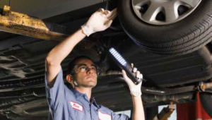 Mechanic under vehicle looking at vehicle