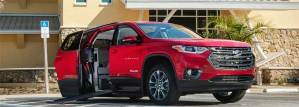 Image of a red chevrolet traverse wheelchair accessible SUV from BraunAbility in front of a building