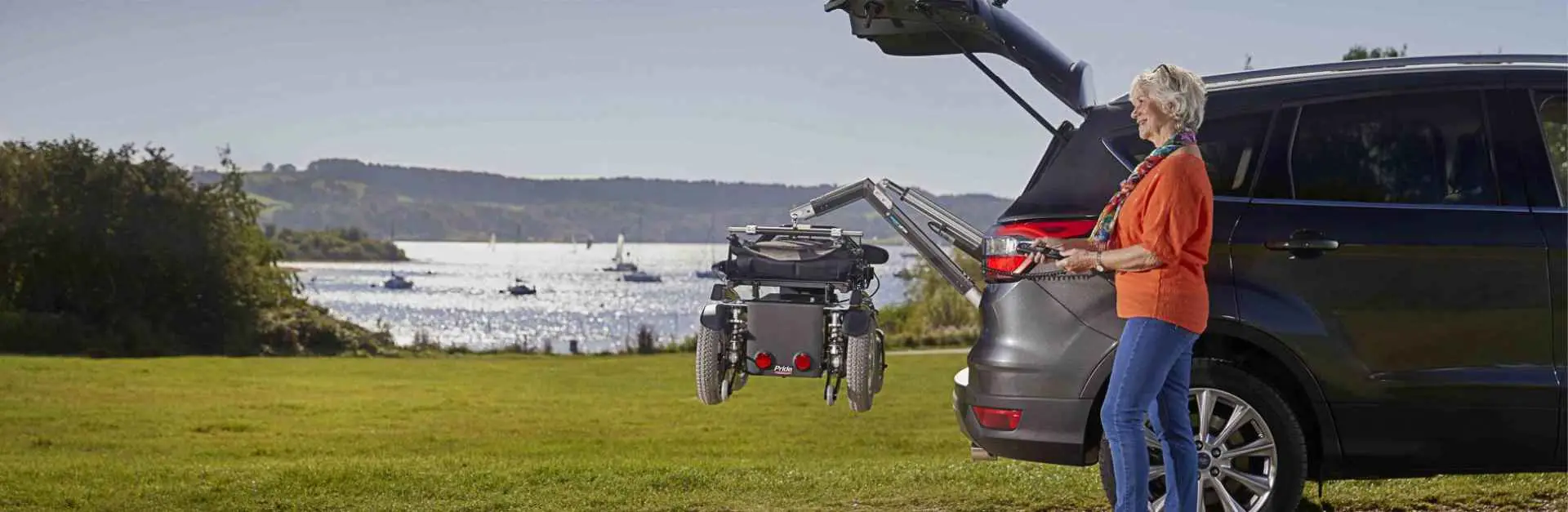 Image of a lady at a lake unloading her mobility scooter using the Smart Lifter scooter lift from Mobility Innovations