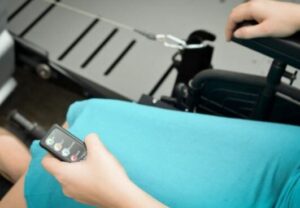 closeup image of a lady in a wheelchair holding a remote control to operate a power pull wheelchair assistant