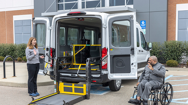 woman and man in wheelchair next to a wheelchair lift van