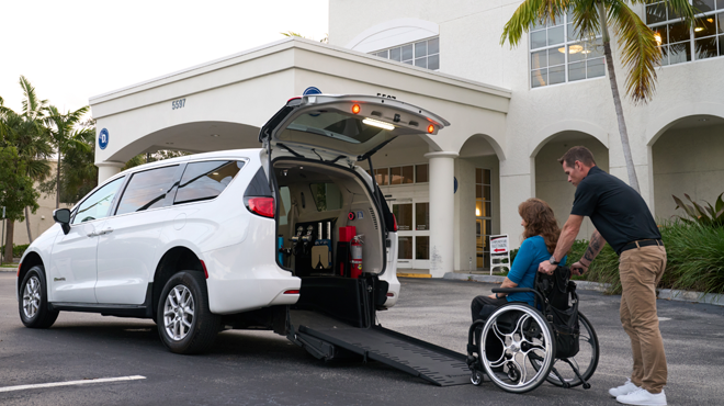 man pushing a women in a wheelchair up a rear-entry ADA van conversion